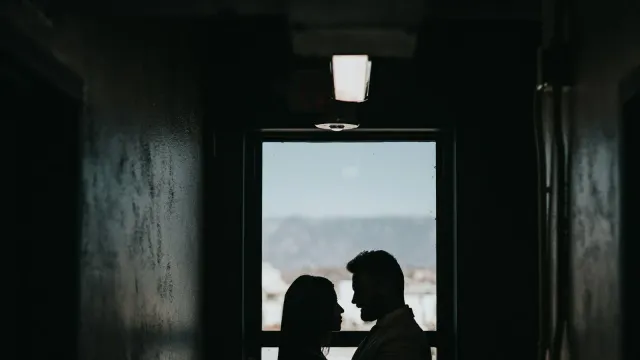 Silhouette eines Paares in einem dunklen Flur vor einem hellen Fenster – Sadist oder Masochist