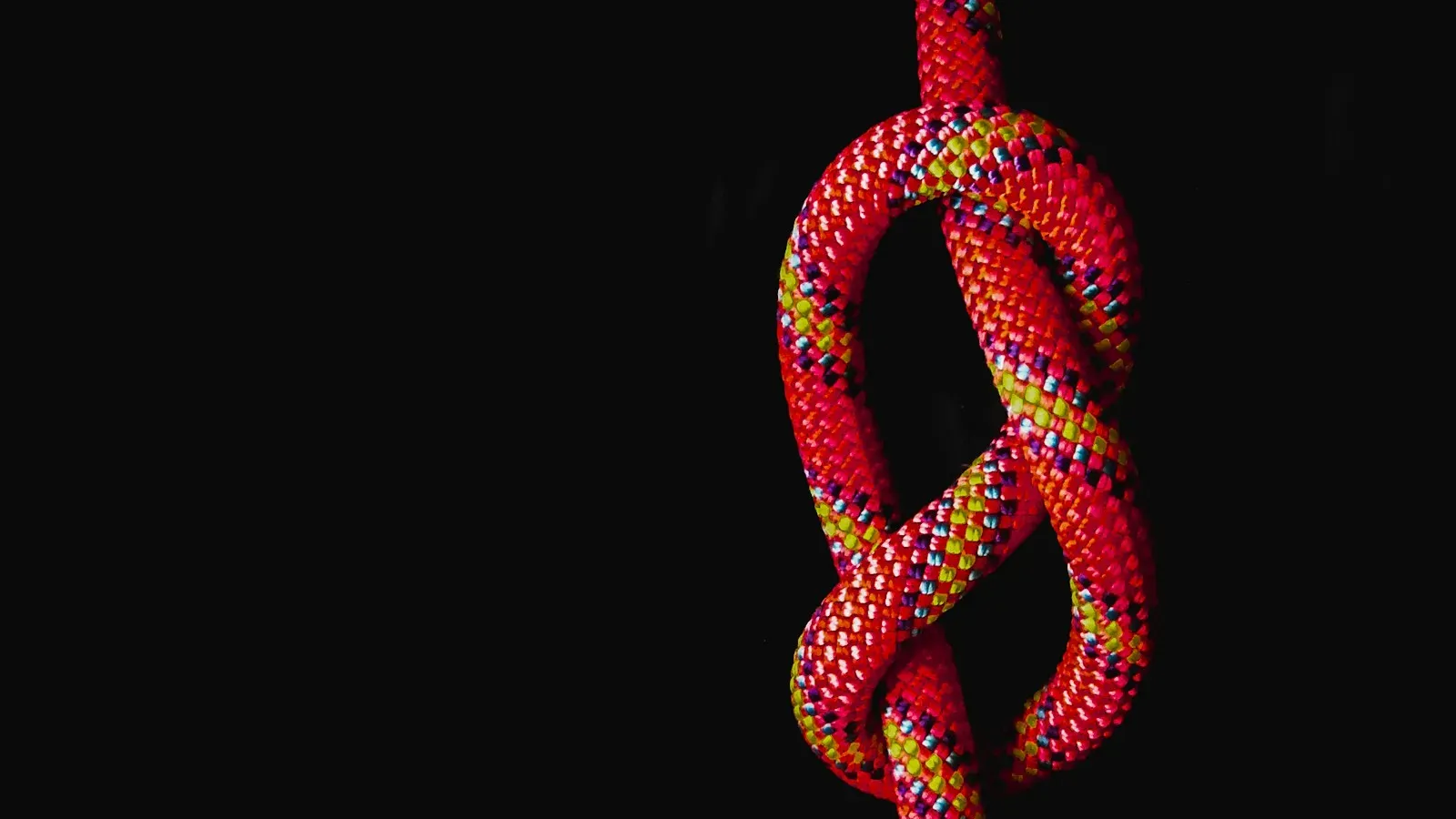 Rotes Seil mit Knoten vor schwarzem Hintergrund – Bondage für Anfänger